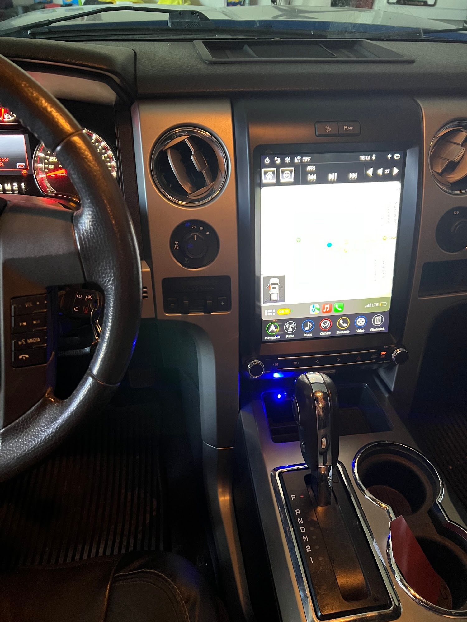 A truck interior with a large touchscreen replacing the center console. The steering wheel, gear shift, and air vents are visible.