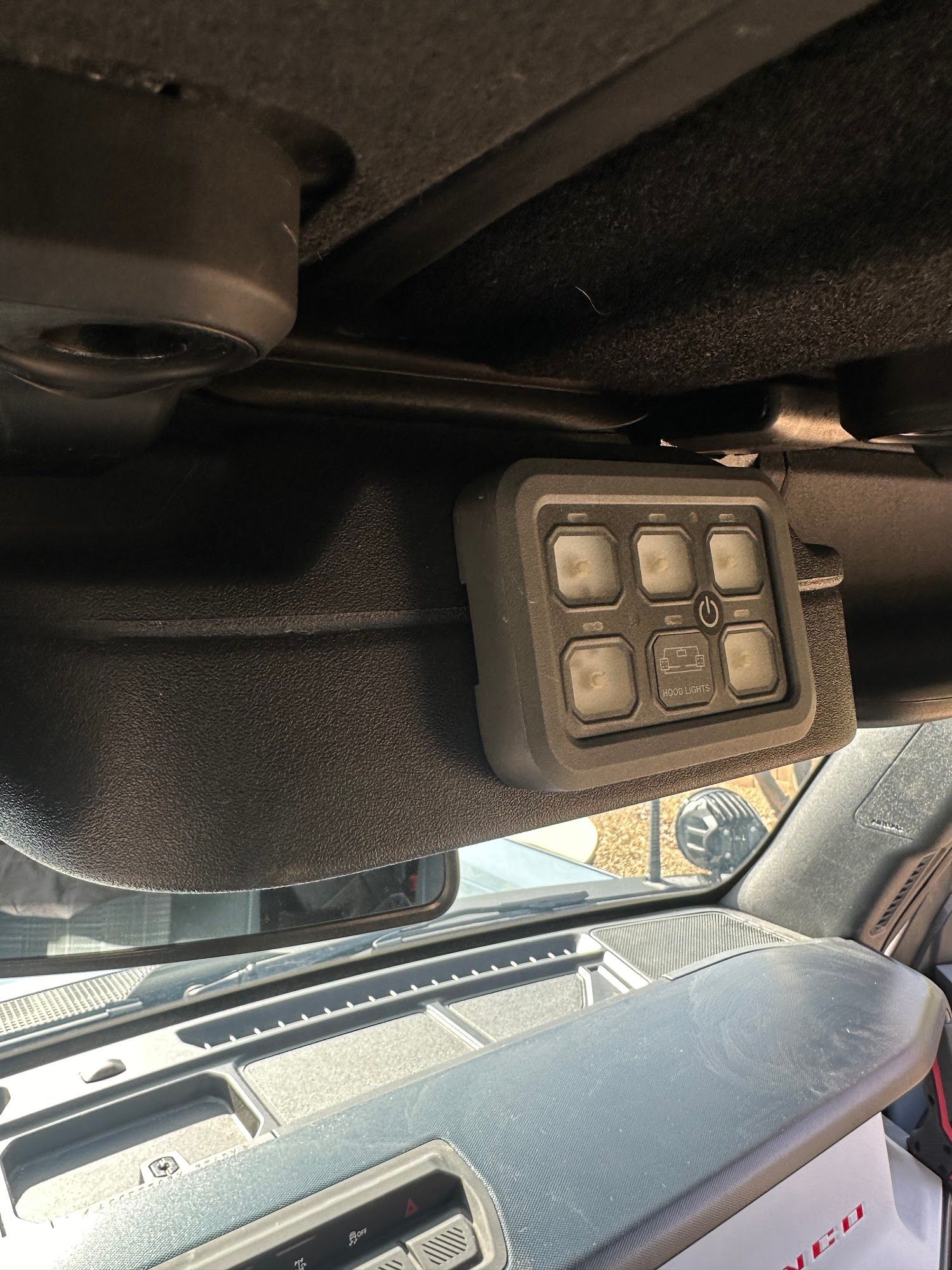 Six-switch panel mounted inside a vehicle above the windshield, likely for controlling aftermarket accessories.