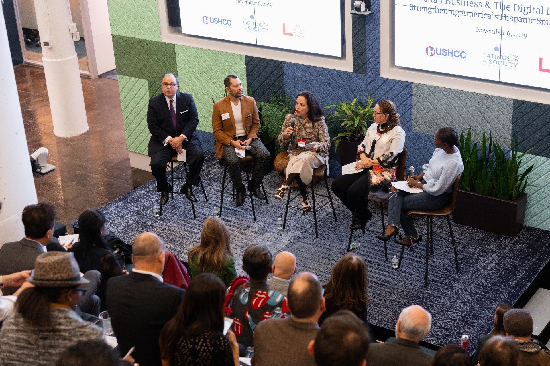 A group of people are sitting in chairs in front of a large screen.