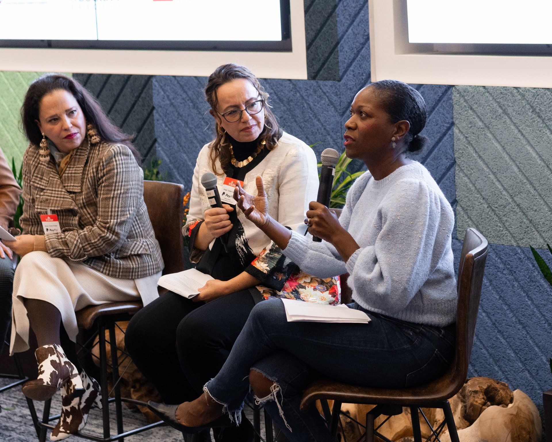 A group of women are sitting in chairs talking into microphones.