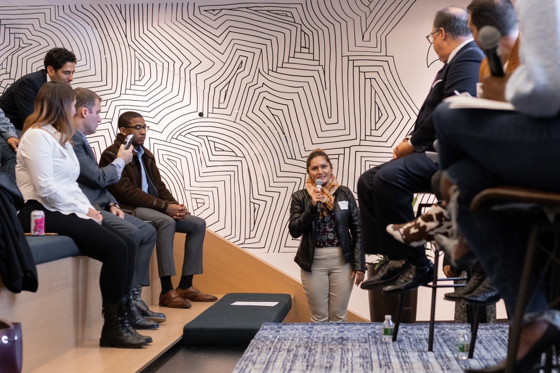 A woman is taking a picture of a group of people sitting in a room.