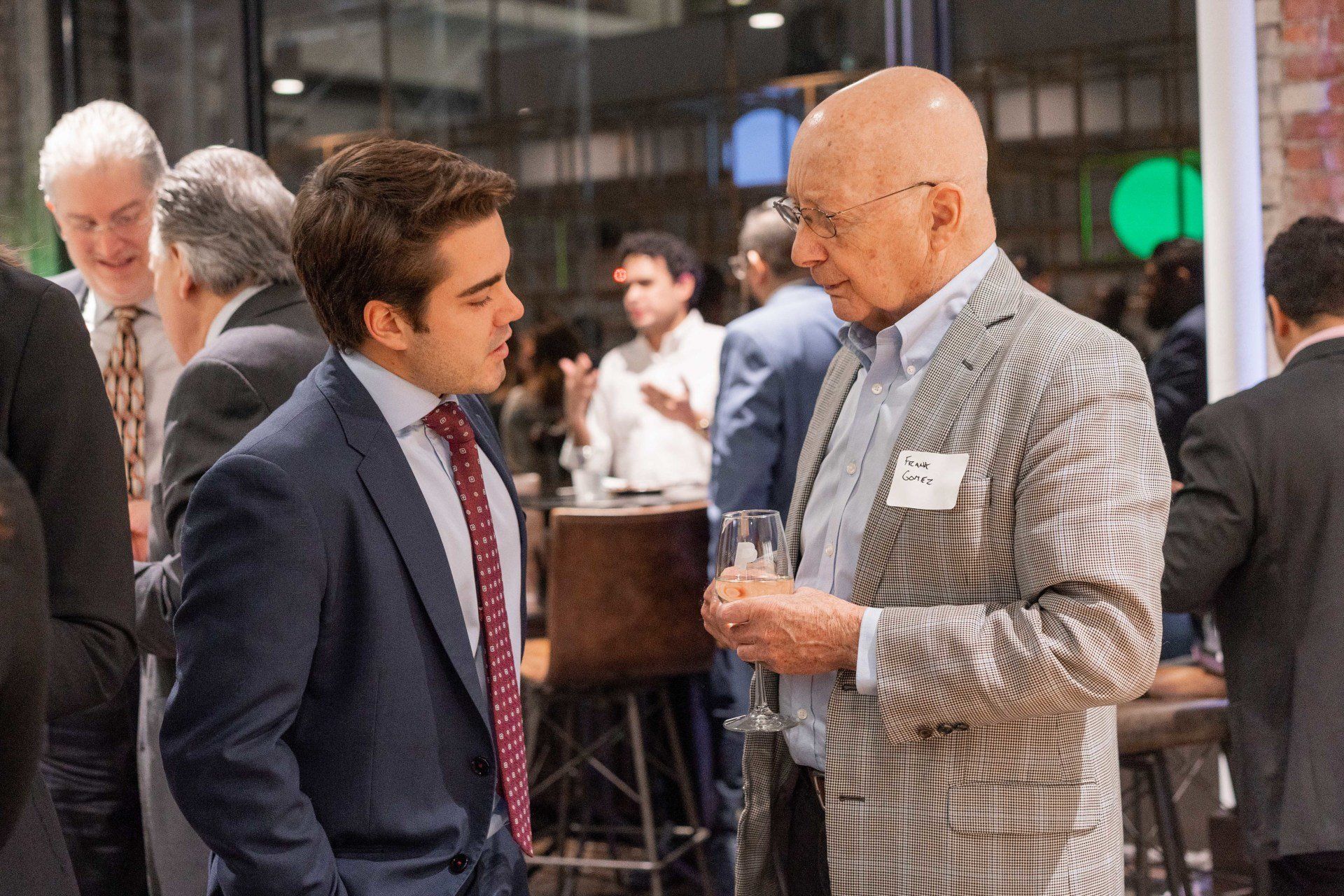 Two men in suits are talking to each other in a crowded room.