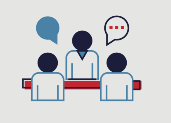 A group of people are sitting at a table talking to each other.
