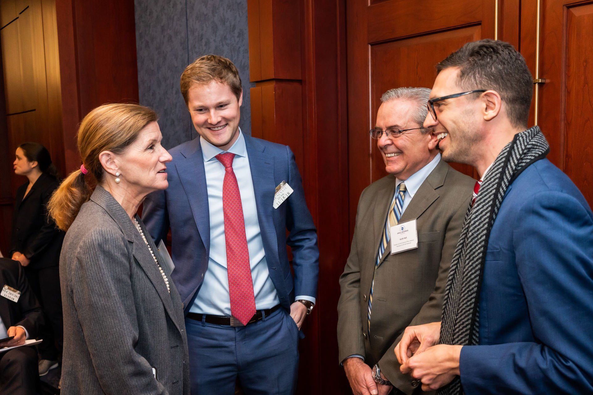 A group of people in suits and ties are talking to each other in a room.