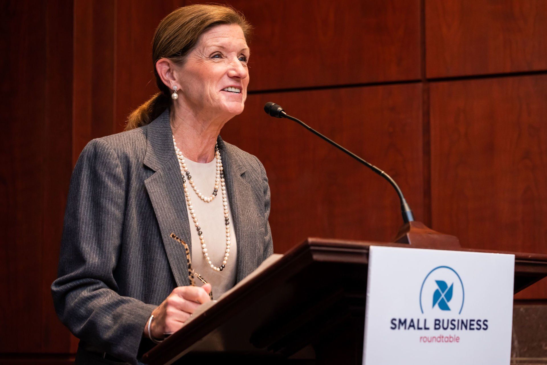 A woman is standing at a podium speaking into a microphone.
