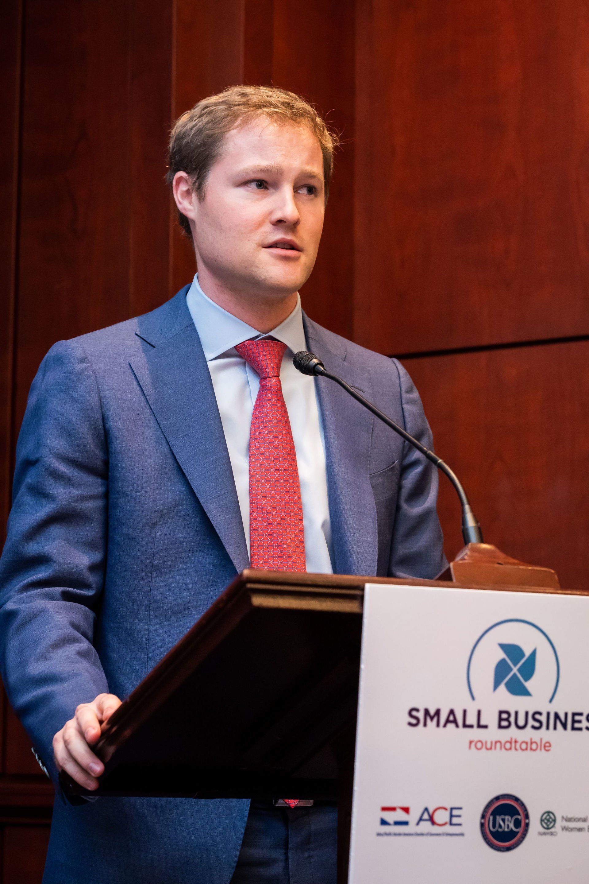 A man in a suit and tie is standing at a podium giving a speech.