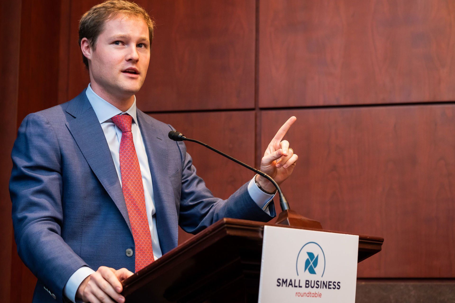 A man in a suit and tie is standing at a podium giving a speech.