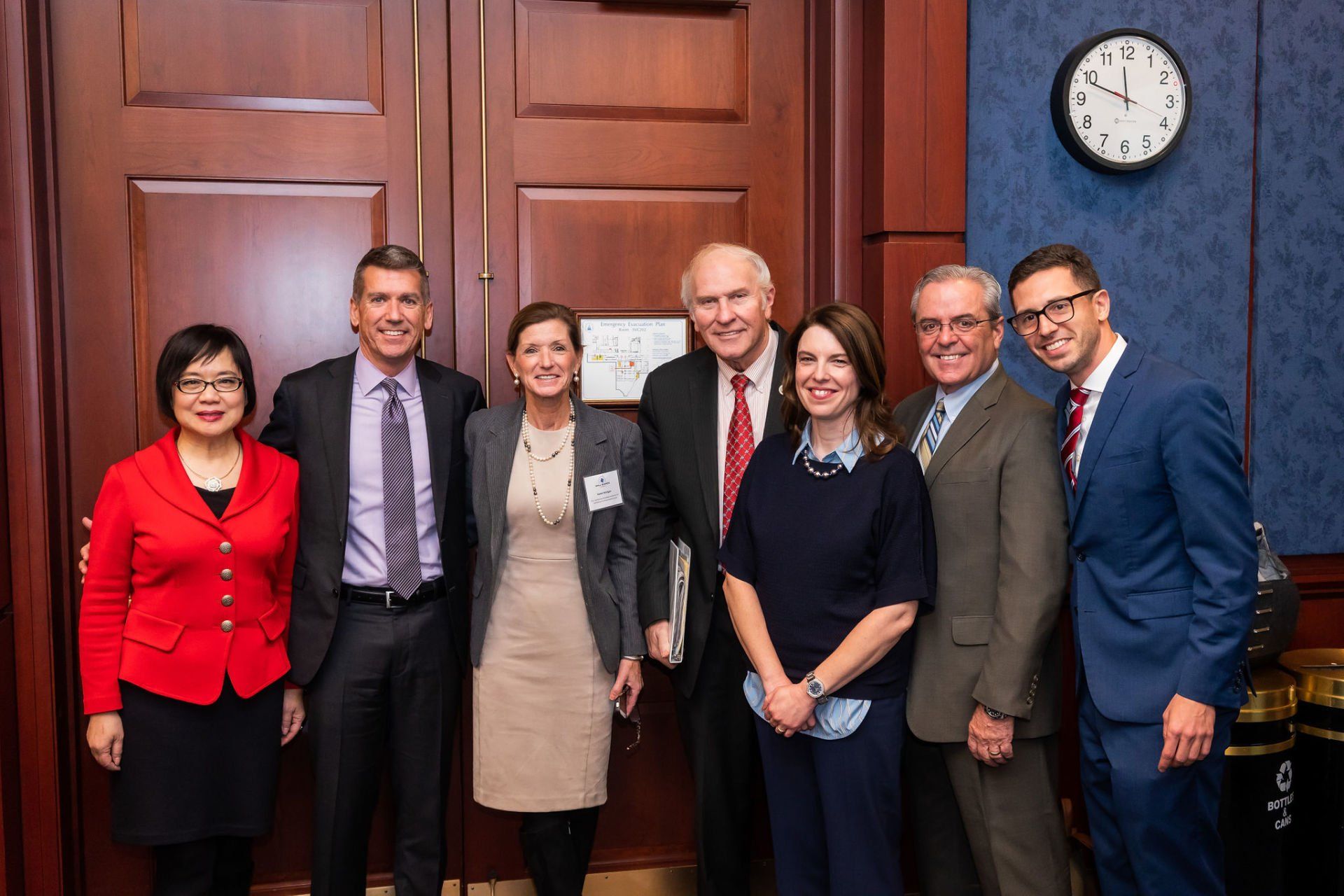 A group of people are posing for a picture in front of a clock.