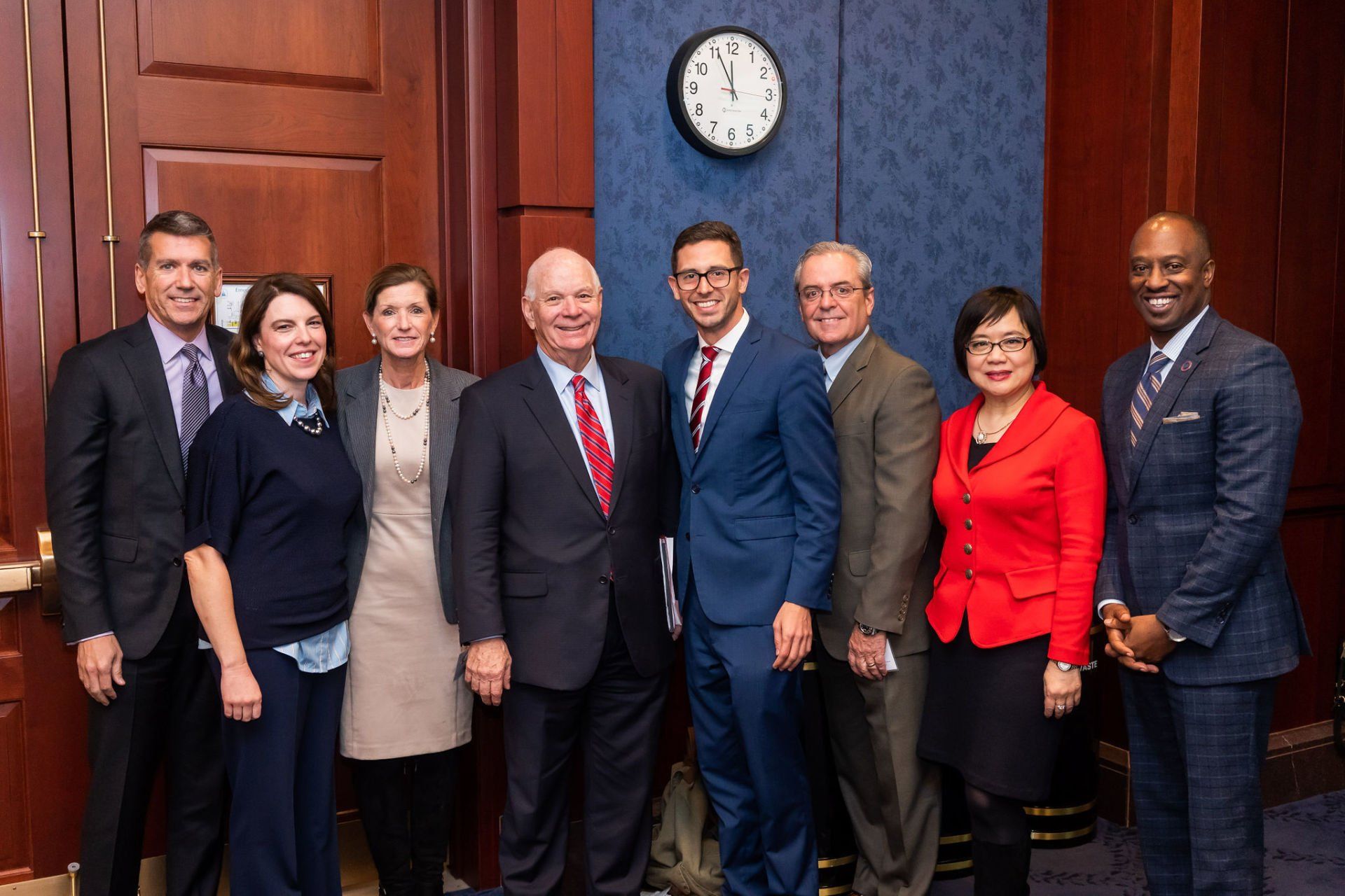A group of people are posing for a picture in front of a clock.