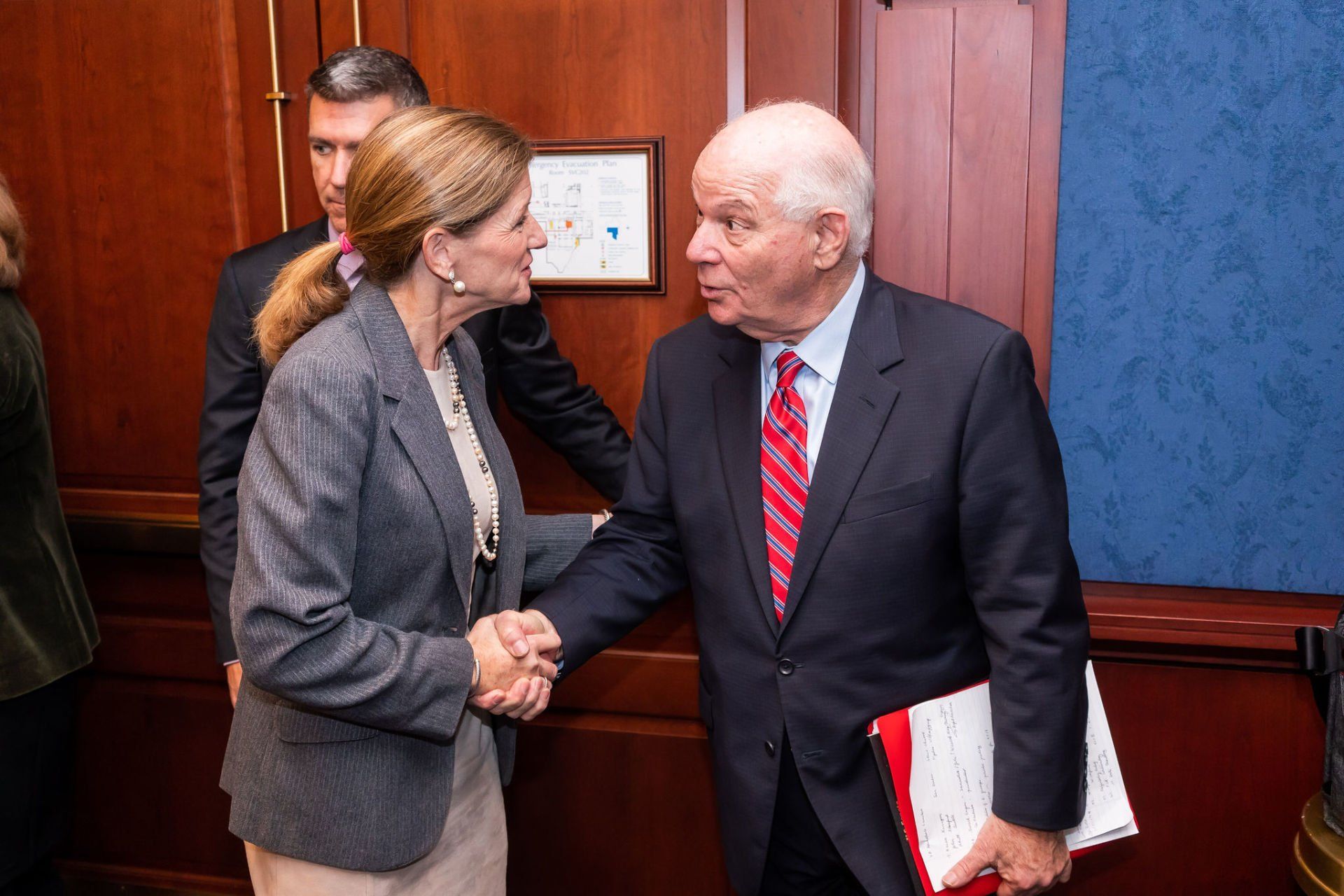 A man and a woman are shaking hands in a room.