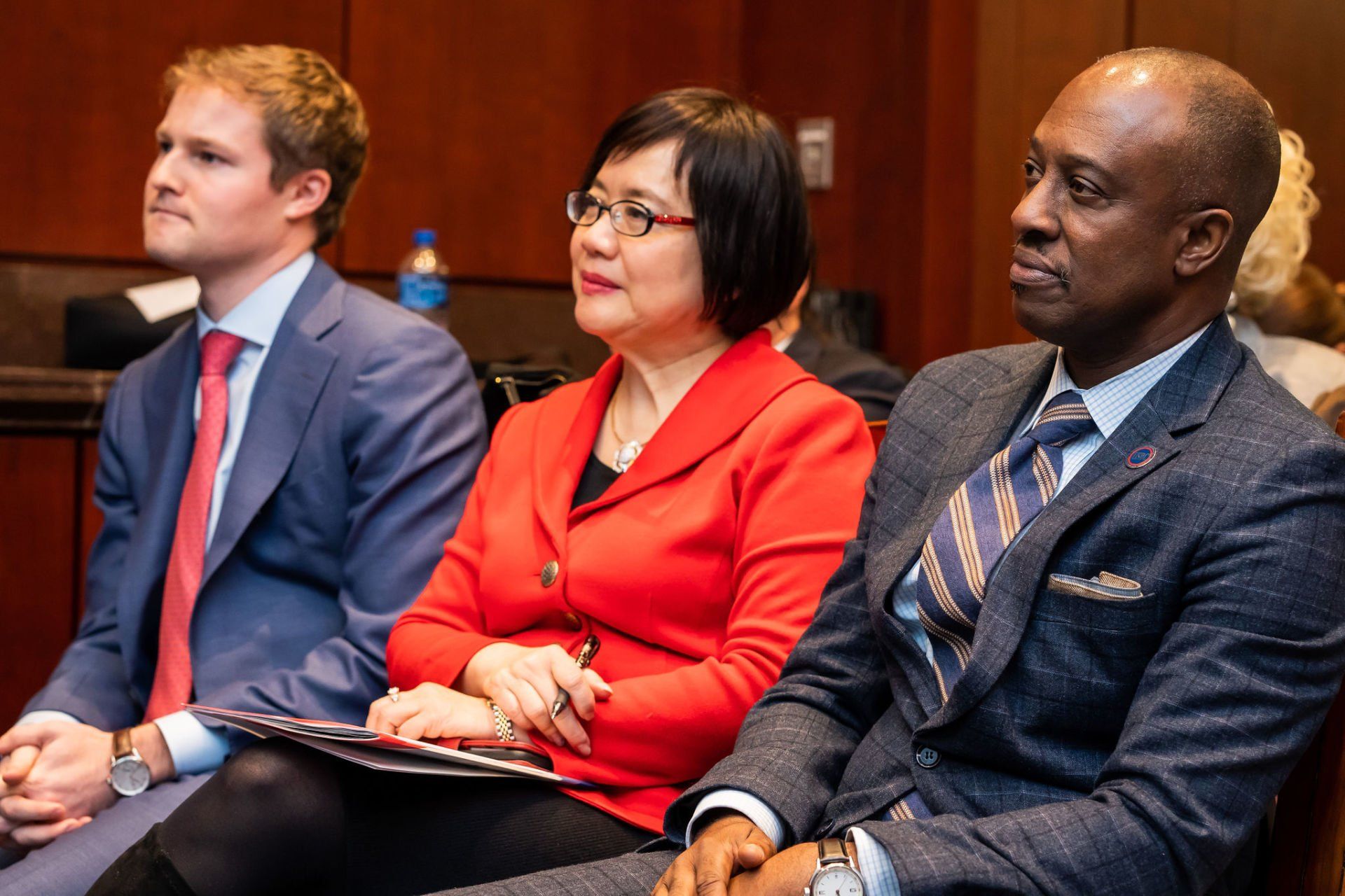 A group of people in suits and ties are sitting in a room.