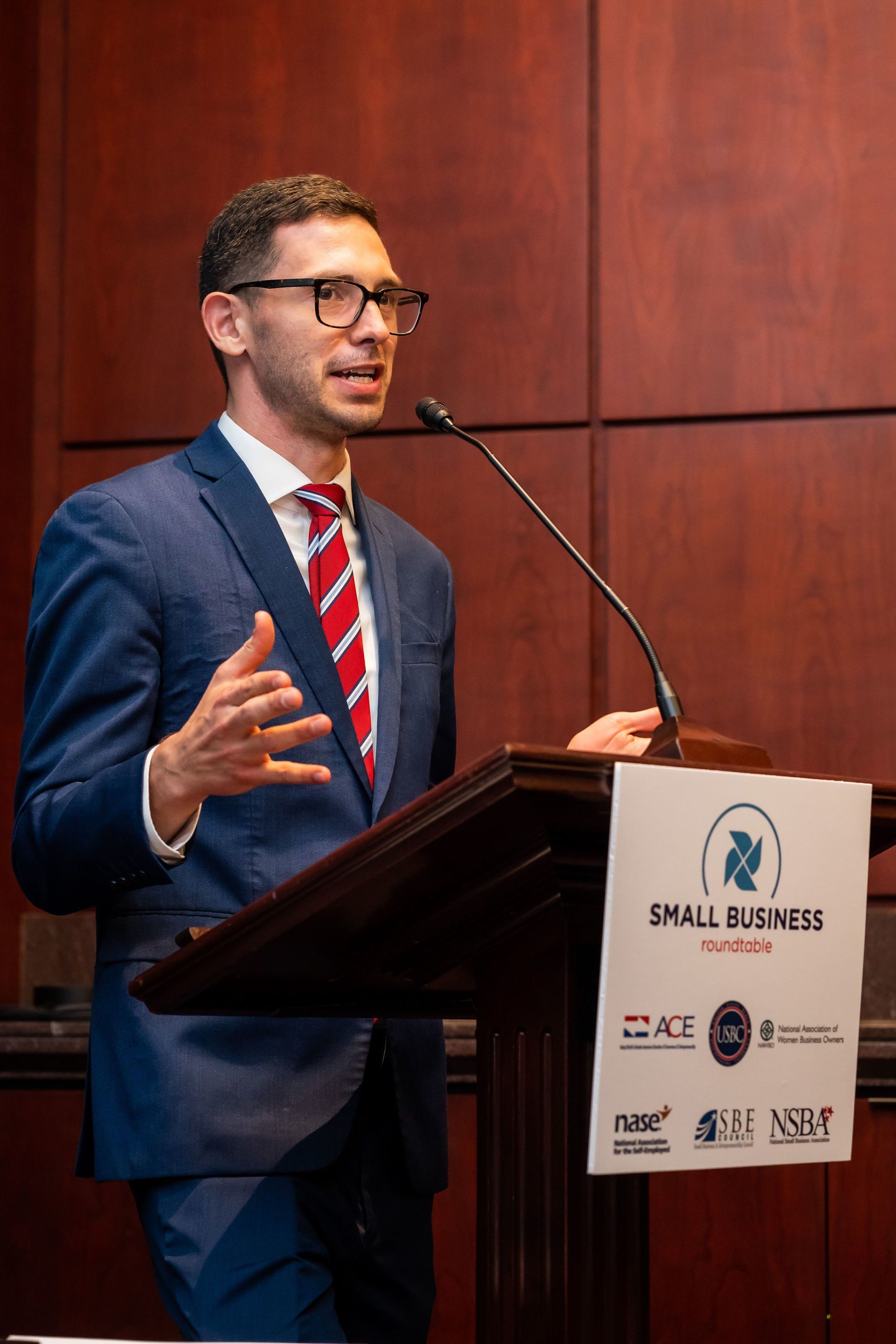 A man in a suit and tie is standing at a podium giving a speech.