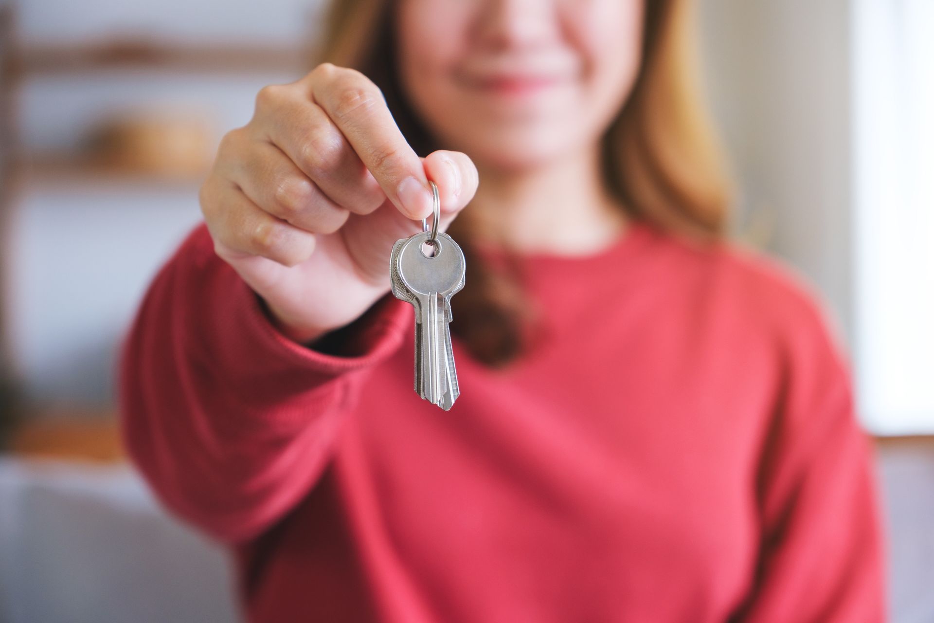 Woman With Red Shirt Holding A House Key to The Camera | Anchorage, AK - Nova Property Woman With Red Shirt Holding A House Key to The Camera | Anchorage, AK - Nova Property