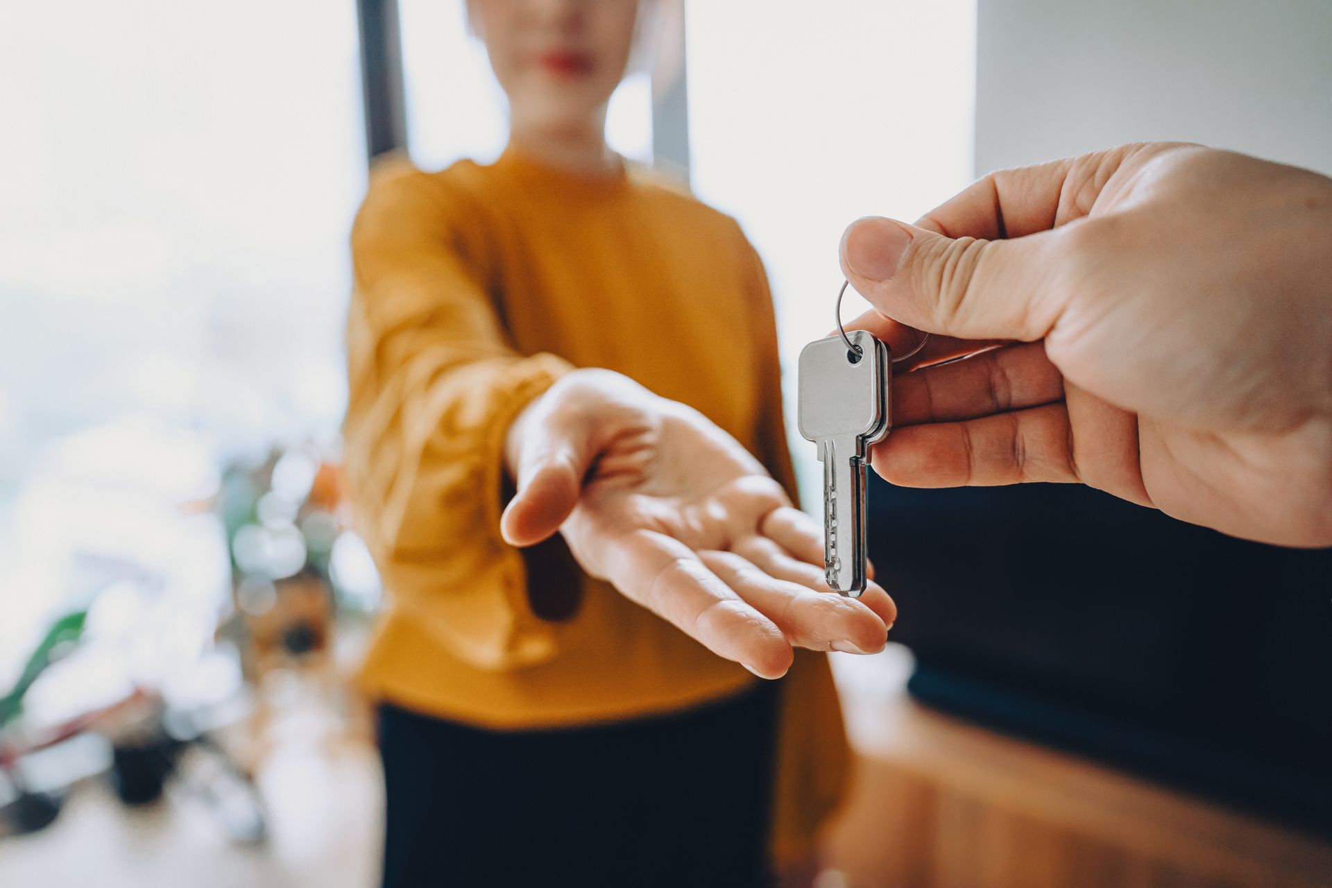 Real estate agent giving keys to young woman, representing property management.