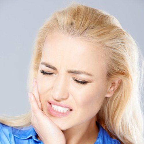A picture showing a woman in distress from wisdom tooth pain