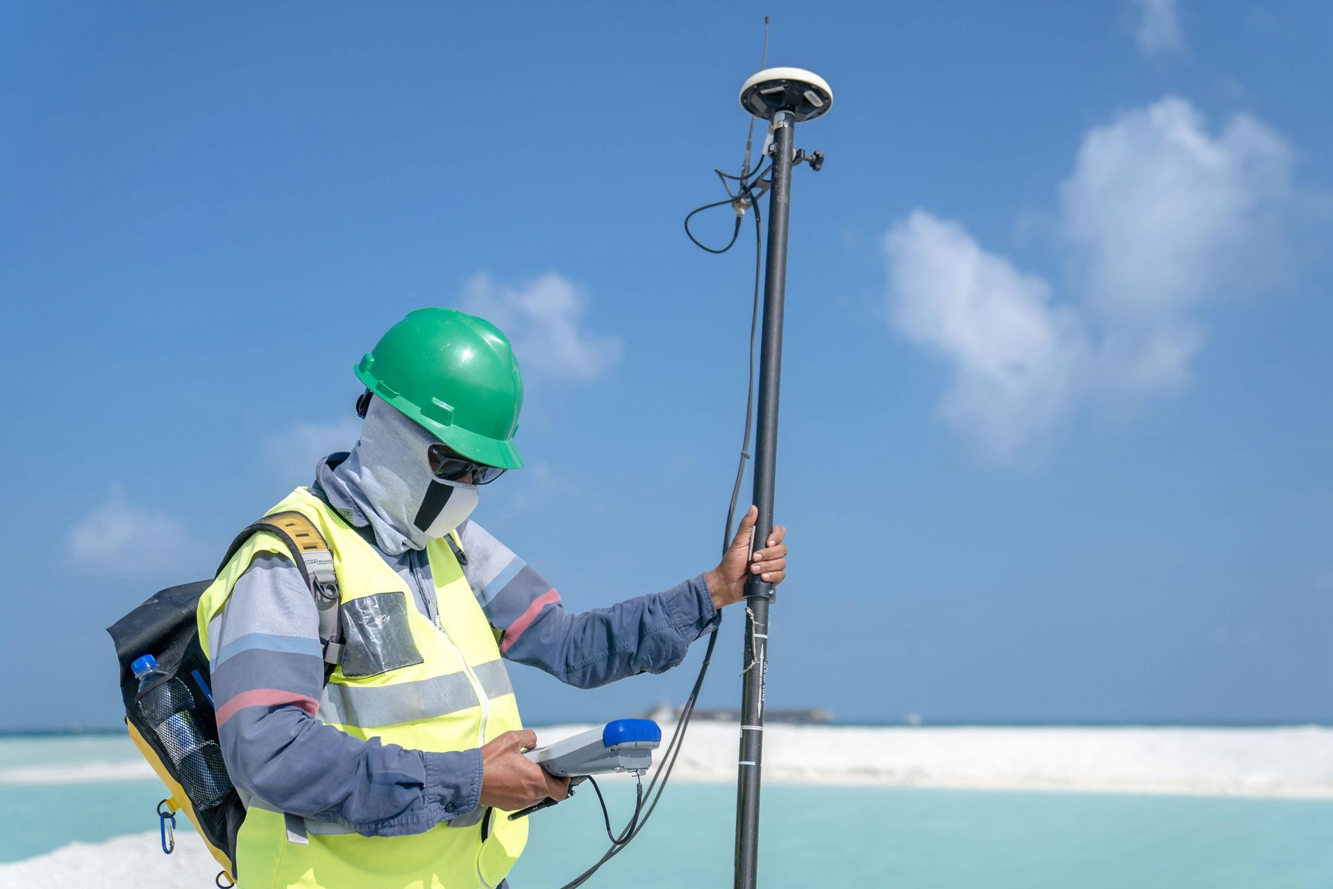 A man wearing a hard hat and a mask is standing next to a pole.