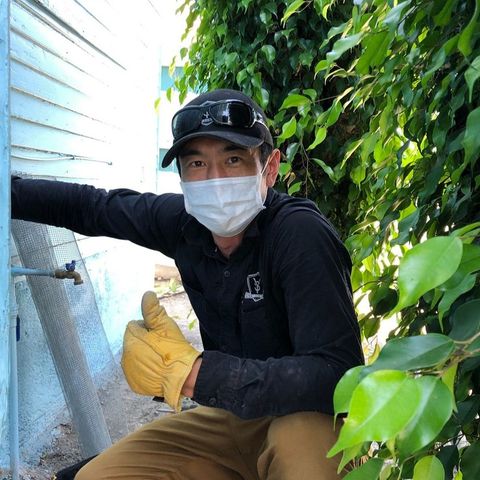 A man wearing a mask and gloves is spraying something with a sprayer.