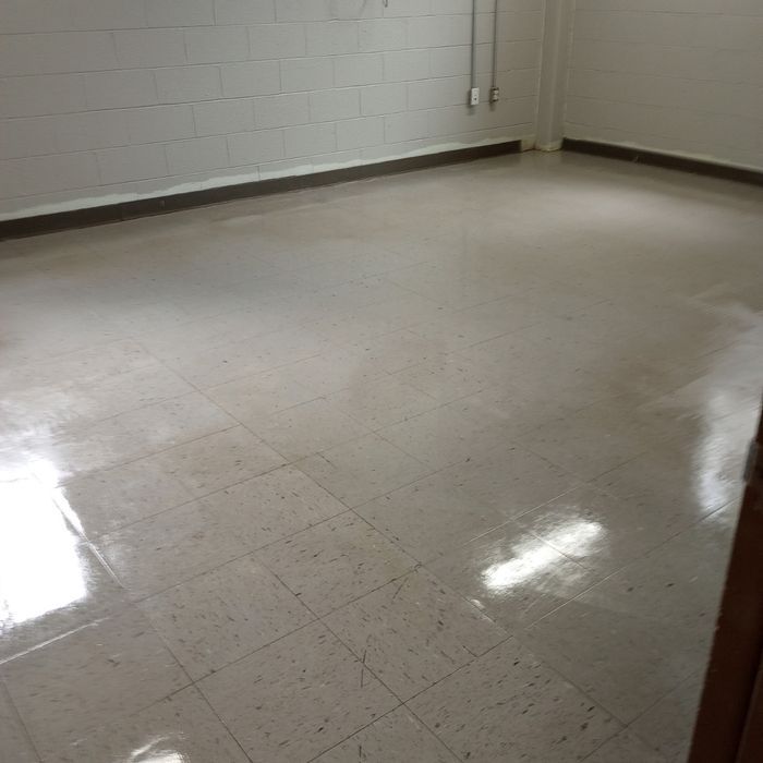 Empty beige-tiled room with white walls and glossy reflections on the floor