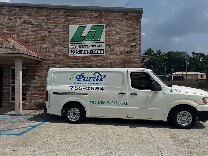 White service van parked by a brick building with a green sign.