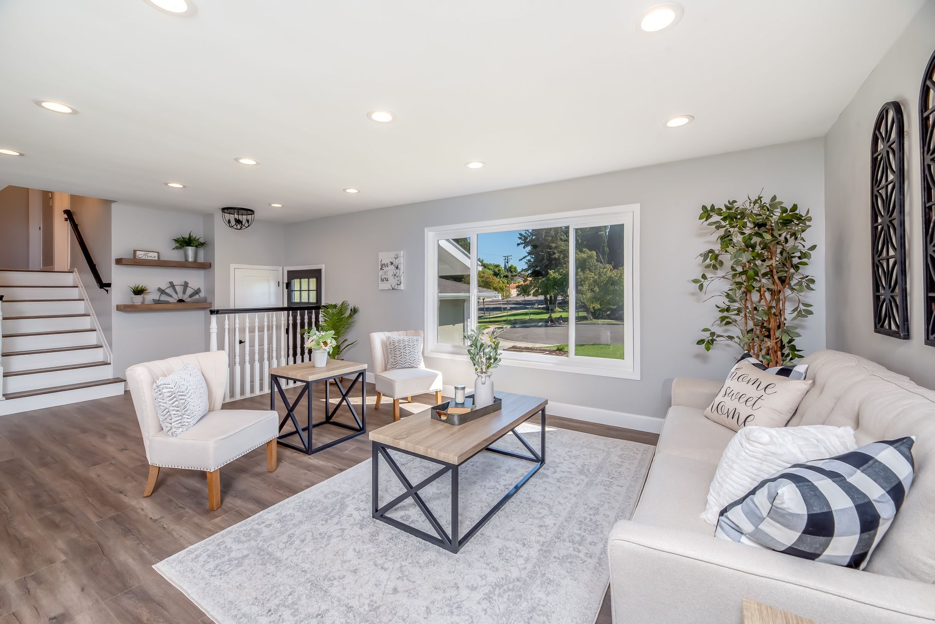 Living room with gray walls, white sofa, wood and metal tables, and a large window.