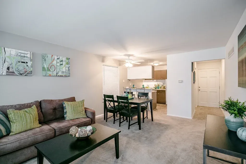 Photo of the living room in the foreground and the dining area in the middleground and the kitchen in the background