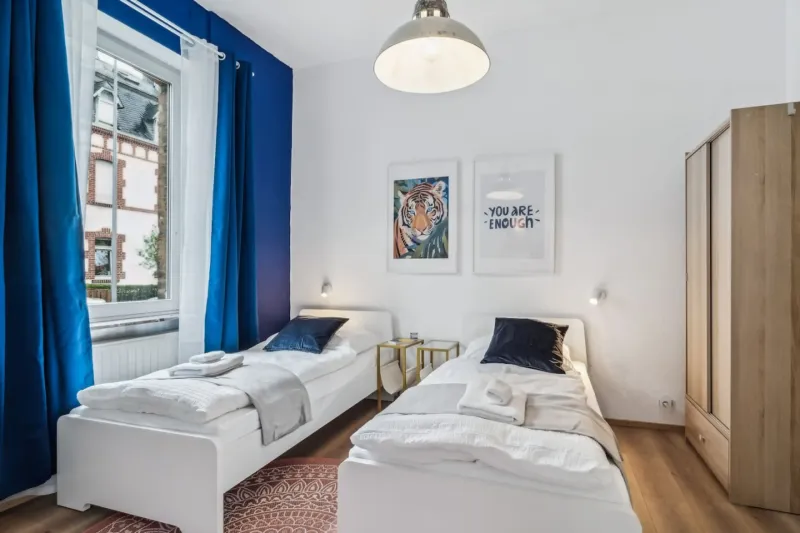 Modern ZachaStay apartment bedroom with blue accent curtains in Koblenz