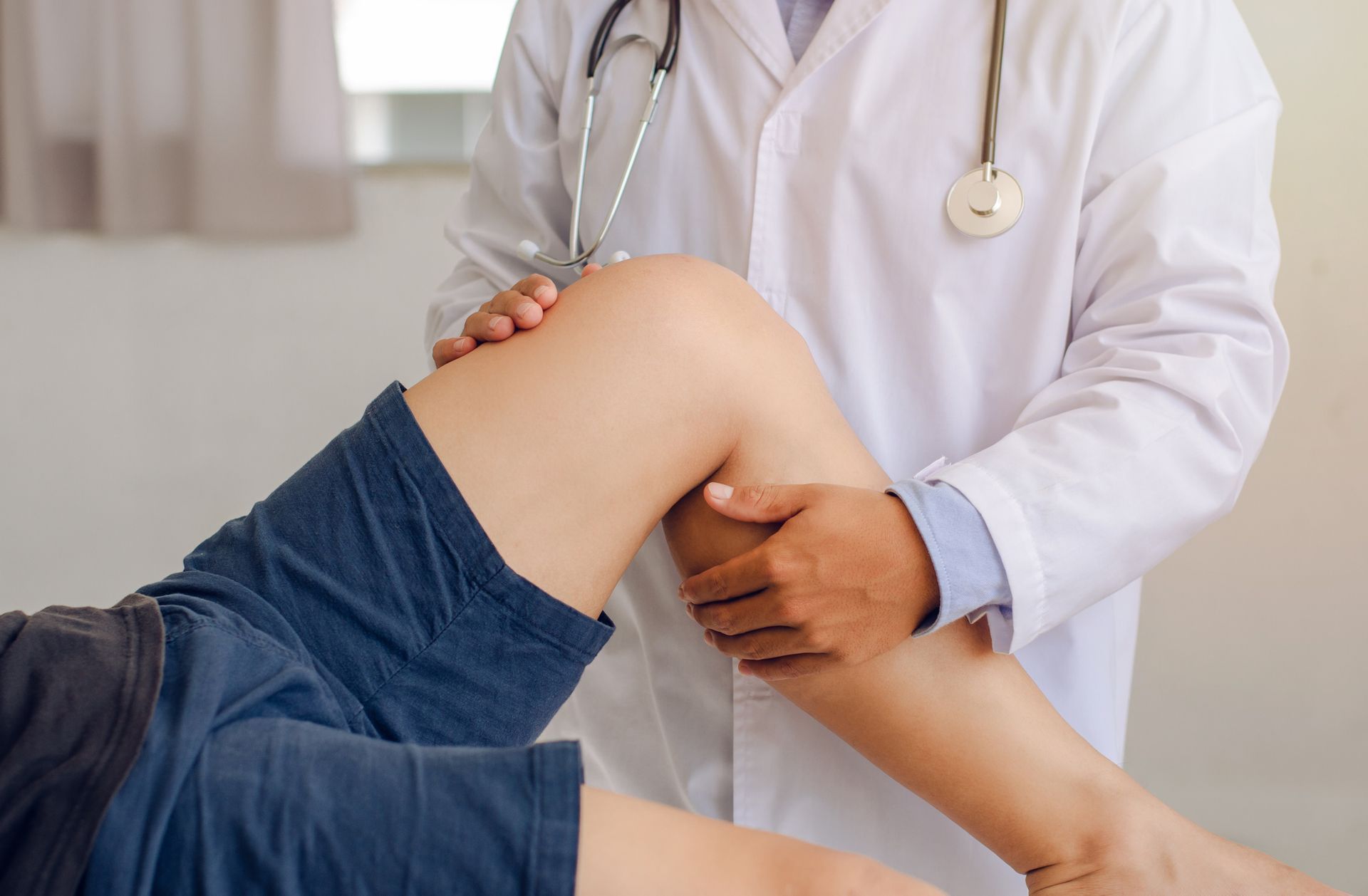 Un medico esamina il ginocchio di un paziente in un ambulatorio.