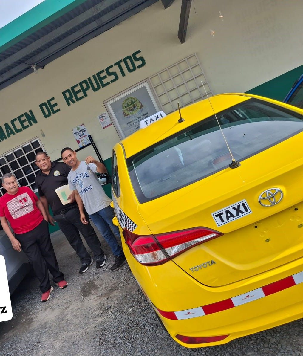 Tres hombres posan con un nuevo taxi amarillo afuera de una tienda 
