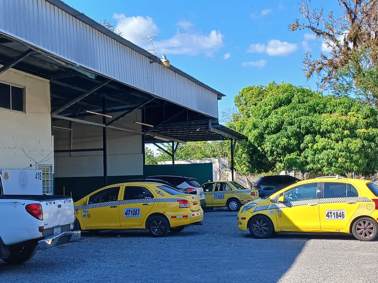 Tres hombres posan con un nuevo taxi amarillo afuera de una tienda 