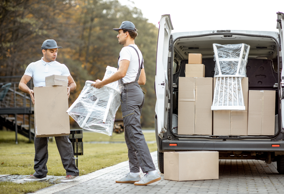 A pair of men carrying furniture and cardboard boxes out of a sprinter van