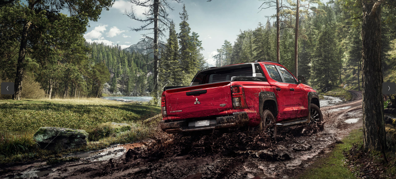 Caminhonete vermelha trafegando por terreno lamacento em uma floresta.