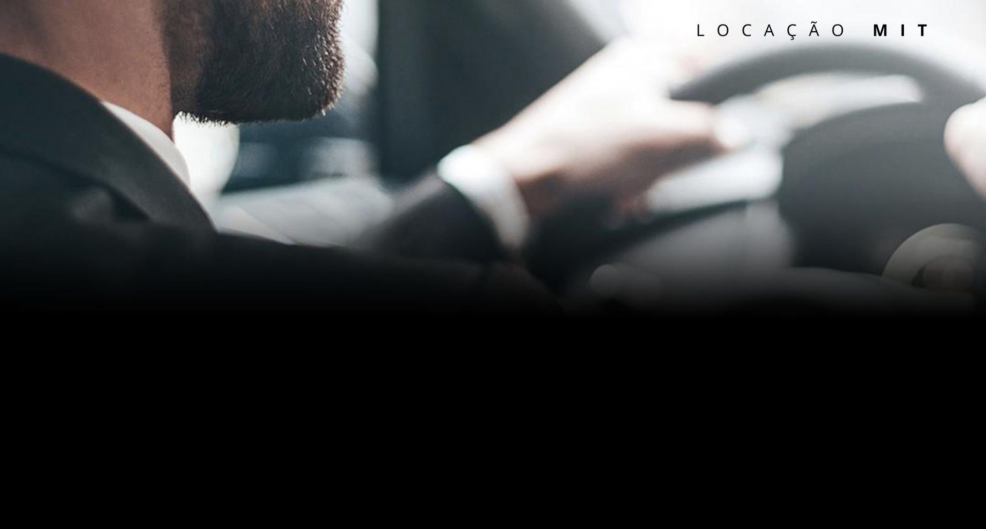 Homem de terno dirigindo um carro, mãos no volante. Interior desfocado, luz forte. Texto: