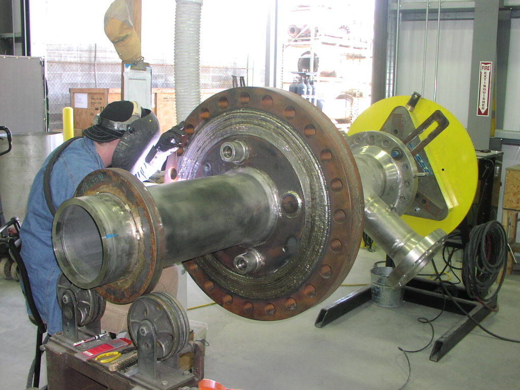 A man is welding a large piece of metal in a factory.