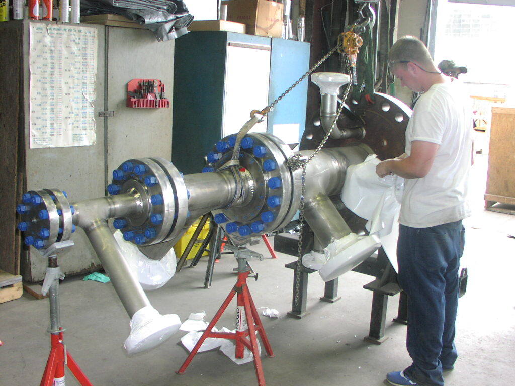 A man in a white shirt is working on a large piece of metal