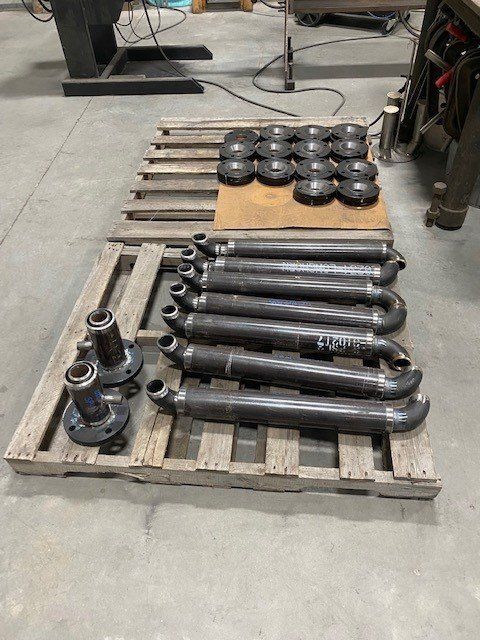 A wooden pallet with a bunch of metal pipes on it.