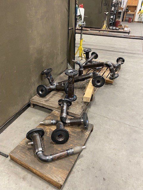 A bunch of metal pipes are sitting on top of a wooden table.