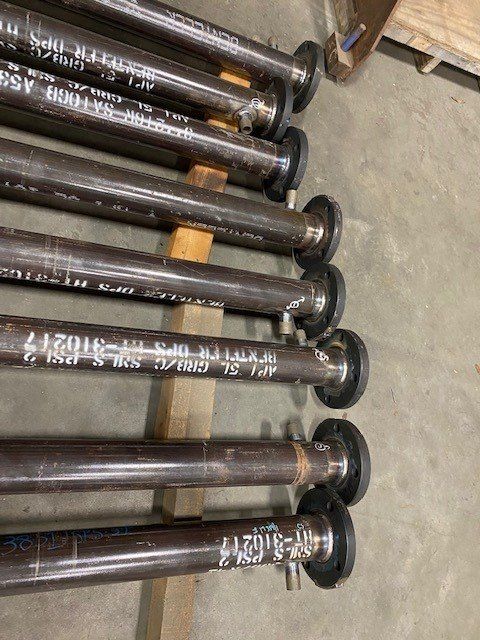 A bunch of metal pipes are stacked on top of each other on a wooden rack.