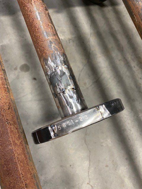 A close up of a rusty metal pipe with a flange on it.