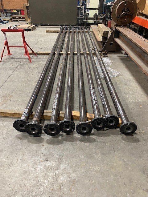 A bunch of metal pipes are stacked on top of each other on a concrete floor.