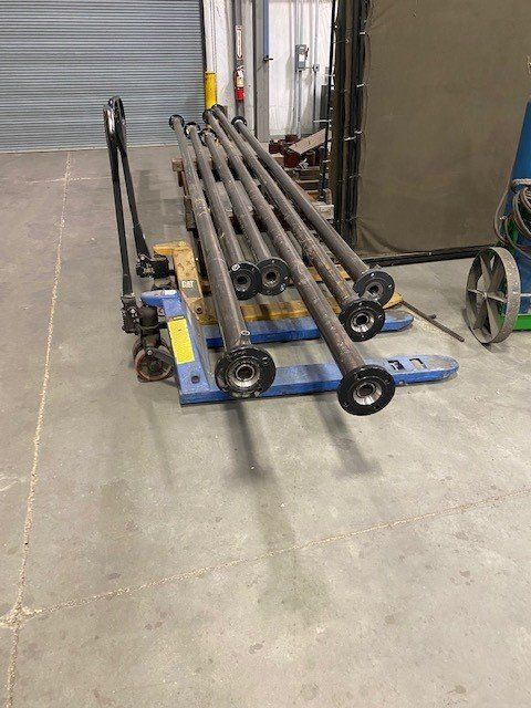 A pallet truck is carrying a bunch of metal pipes in a warehouse.