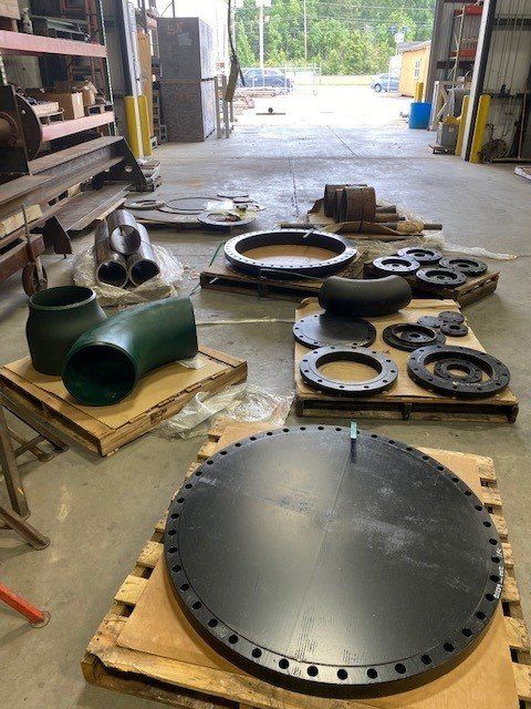 A bunch of metal pipes are sitting on pallets in a factory