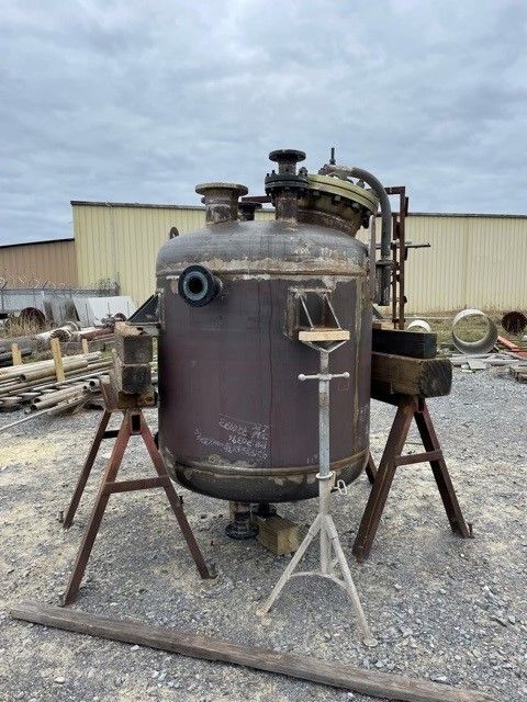 A large metal tank is sitting on top of a wooden stand.