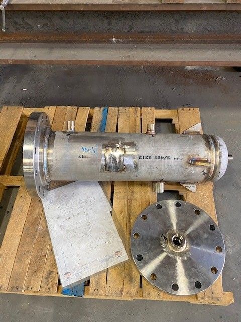 A stainless steel pipe is sitting on top of a wooden pallet.