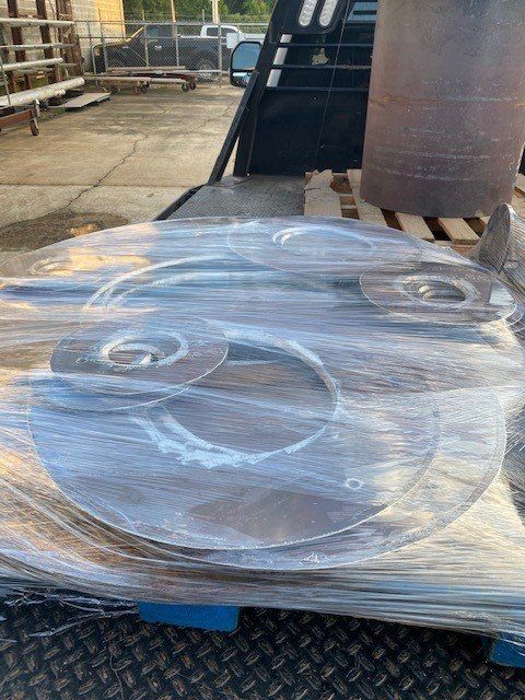 A large piece of metal is wrapped in plastic and sitting on top of a pallet.