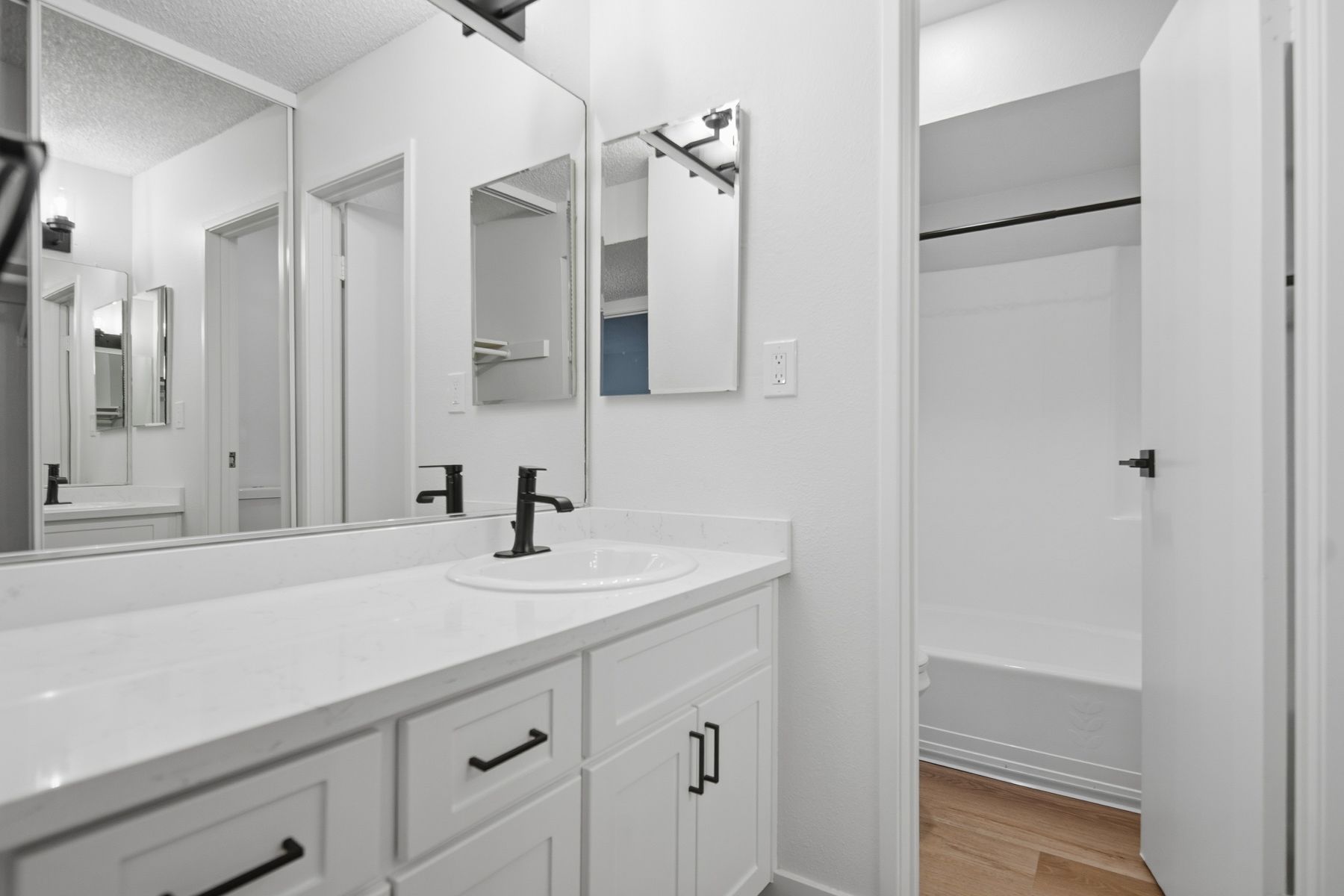 White bathroom with vanity, mirror, and open doorway to closet.
