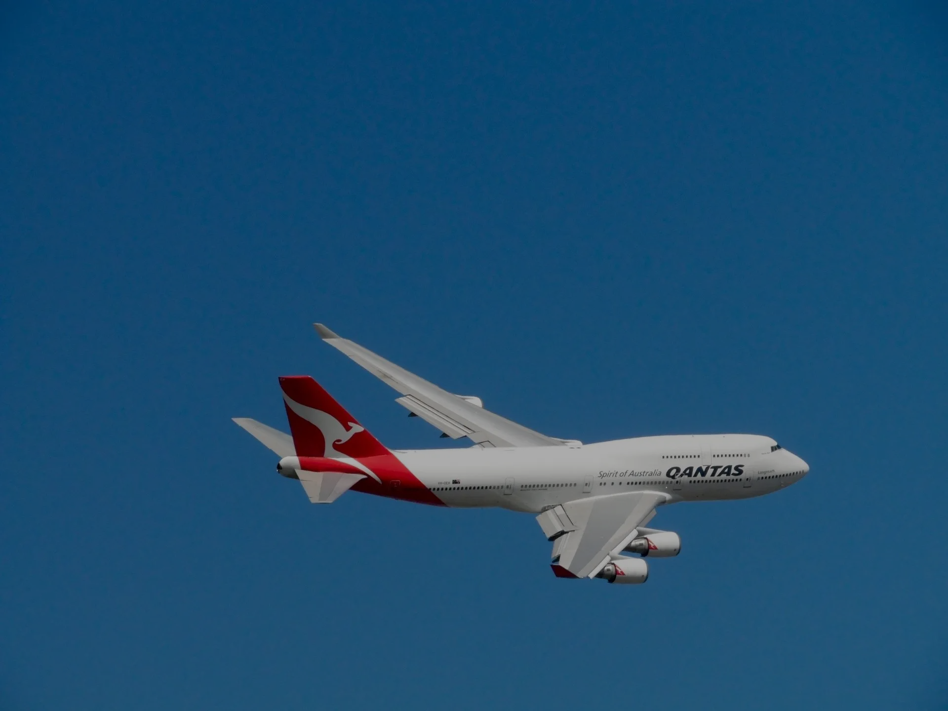 Avión Boeing 747 de Qantas contra un cielo azul brillante.