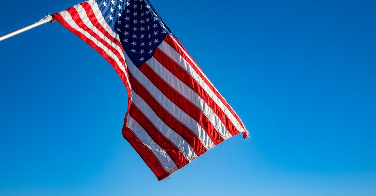 Una bandera estadounidense ondea en el viento contra un cielo azul.