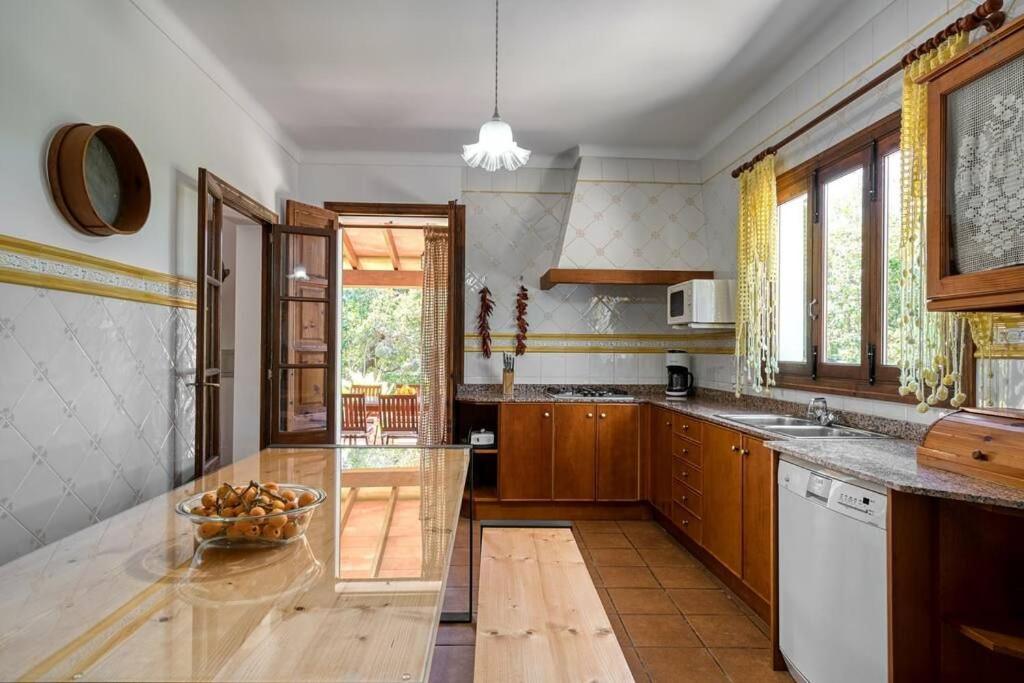 Cocina con gabinetes de madera, encimera larga y puerta abierta a un patio exterior.