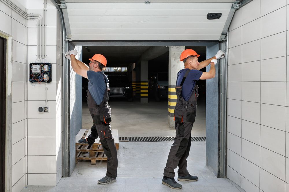 Two Men Are Working On A Garage Door — Upright Garage Doors In Chipping Norton, NSW