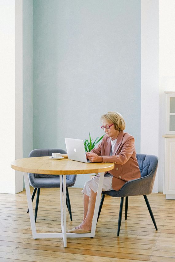 A woman is sitting at a table using a laptop computer.